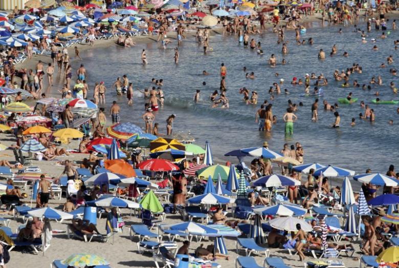 People sunbathe and swim on a beach in Benidorm