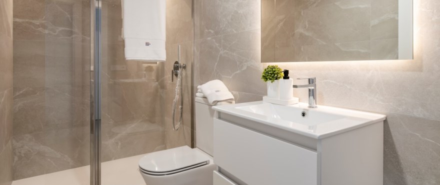 Modernes, voll ausgestattetes Bad mit installierten Duschwänden, in der Wohnanlage Iconic